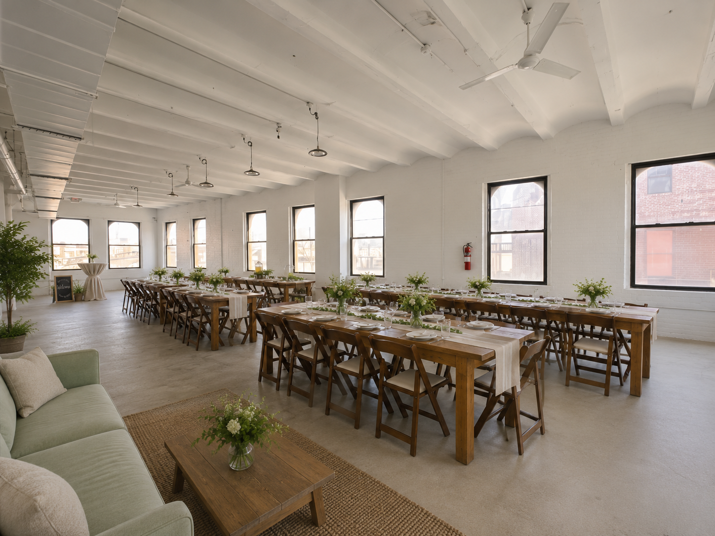 Rows of dressed dinner tables running the length of the light-filled loft, seen from the lounge area